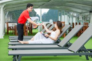 a woman laying on a bench with a man at Le Journey Calypso Pool Cruise Ha Long Bay in Ha Long