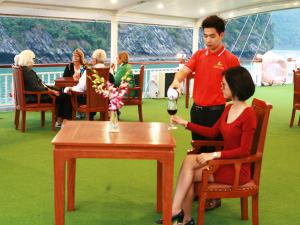 Un homme versant un verre de vin à une femme dans l'établissement Le Journey Calypso Pool Cruise Ha Long Bay, à Hạ Long