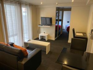 sala de estar con sofá y TV de pantalla plana en Apartments on Chapman, en Melbourne