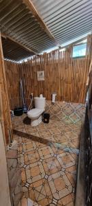 uma casa de banho com WC num quarto com paredes de madeira em Tetebatu Hostel em Tetebatu