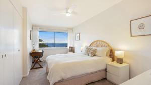 a white bedroom with a bed and a window at 'Surfside' by HolidayCo in Killcare
