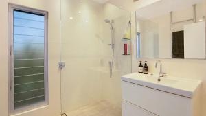 a white bathroom with a sink and a shower at 'Surfside' by HolidayCo in Killcare