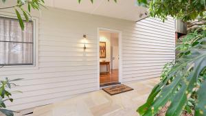a white house with a door leading to a hallway at 'Surfside' by HolidayCo in Killcare
