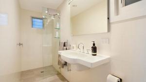 a white bathroom with a sink and a mirror at 'Surfside' by HolidayCo in Killcare +11 photos