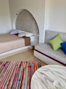 a room with two beds and a couch and a rug at Kostas Studios in Faliraki