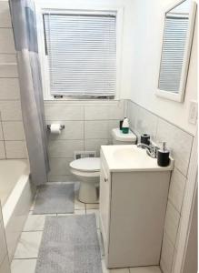 a white bathroom with a toilet and a sink at Queen Suite - Hot Tub - 10 Mins to Downtown Room 2 in Atlanta