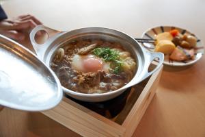 a pot of soup on top of a wooden tray at REF Matsuyama City Station by VESSEL HOTELS in Matsuyama