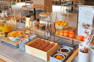 a buffet of food with oranges and other foods at REF Matsuyama City Station by VESSEL HOTELS in Matsuyama