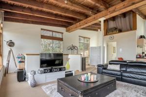 a living room with a black leather couch and a tv at Escape To Narrabeen @ Sydney Northern Beaches - Home Away From Home in Narrabeen