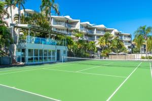 a tennis court in front of a hotel with palm trees at Noosa Hill Resort in Noosa Heads