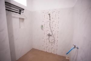 a bathroom with a shower in a white wall at Fresh Inn in Probolinggo