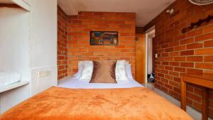 Un dormitorio con una pared de ladrillo y una cama. en Gran Caribe Hotel, en Medellín