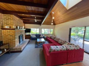 a living room with a red couch and a brick fireplace at A Hidden Bush Delight in Dunsborough