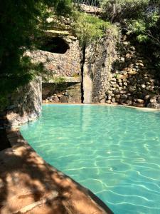 a pool of blue water next to a rock wall at Tree house in Ngong