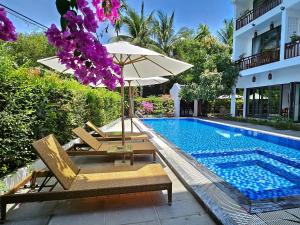 uma piscina com cadeiras e um guarda-sol ao lado de um edifício em Chiều Hạ Village em Hoi An