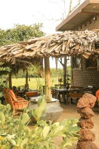 un patio con sombrilla de paja, sillas y mesas en Monsoon Eco Resort - Whisky point Arugambay, en Pottuvil