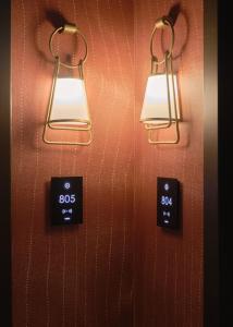 two lights are hanging on a wall with a clock at The Motley Hotel in Melbourne