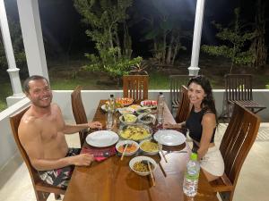 Un uomo e una donna seduti a un tavolo con del cibo di Forest Tree Top Holiday Resort a Buttala