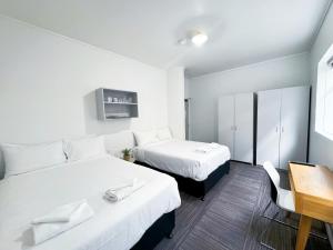 140 Ghuznee Hostel في ويلينغتون: غرفة بسريرين وطاولة ومكتب