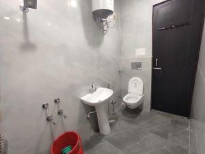a bathroom with a white toilet and a sink at Hotel O AVS in Morādābād