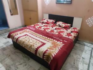a bedroom with a bed with a red and white comforter at Hotel O AVS in Morādābād