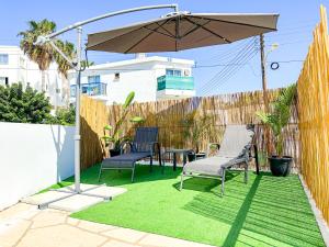 un patio con 2 sillas y una sombrilla en Vacation mode Apartment, en Ayia Napa