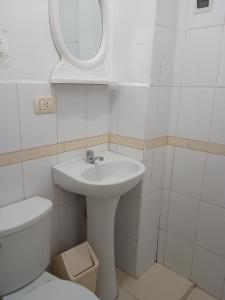 a white bathroom with a sink and a toilet at Hotel TIKA AYNA Cerca a la plaza de Armas CUSCO in Cusco