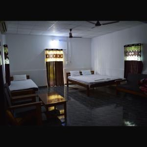 a room with two beds and a table and chairs at Falcon Jungle Resort in Jyoti Gaon