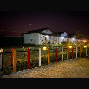 a fence in front of a building at night at Falcon Jungle Resort in Jyoti Gaon