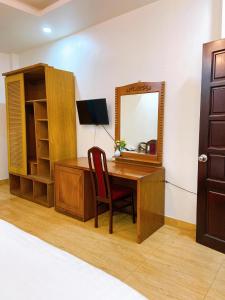 a desk with a mirror and a chair in a room at Hotel Hoàng Lộc Phát in Cái Răng