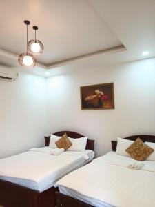 two beds in a room with white walls at Hotel Hoàng Lộc Phát in Cái Răng