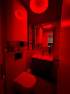 a red bathroom with a toilet and a sink at Sétány Kuckó Apartman in Balatonfüred