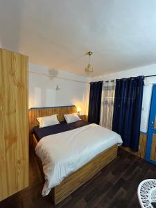 a bedroom with a large bed with blue curtains at Tiny Spot Hostel in Manāli