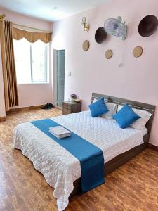 um quarto com uma cama grande e almofadas azuis em NA NA Homestay em Ilha de Cát Bà