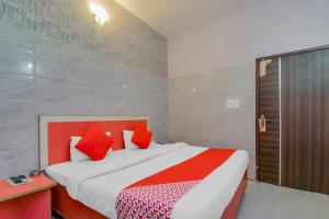 um quarto com uma cama grande e almofadas vermelhas em Collection O Goodwill Hotel em Jamu