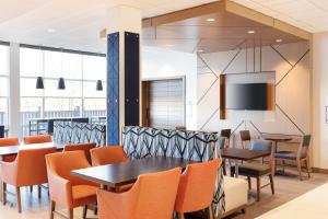 a dining room with tables and chairs and a flat screen tv at Holiday Inn Express Hocking Hills-Logan by IHG in Logan