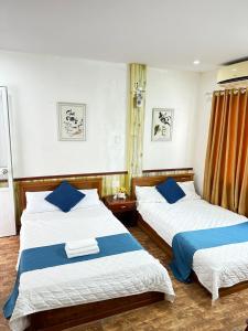 um quarto com 2 camas e almofadas azuis em NA NA Homestay em Ilha de Cát Bà