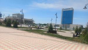 an empty street with a tall building in the background at Коктем 16 in Taldykorgan