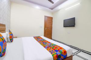 um quarto com uma cama e uma televisão na parede em FabHotel Starlight em Nova Deli
