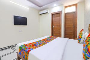 um quarto com uma cama com um cobertor colorido em FabHotel Starlight em Nova Deli