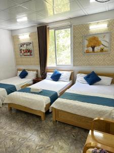 um quarto com três camas e uma janela em NA NA Homestay em Ilha de Cát Bà
