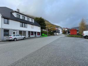 an empty street with a white house and a car at BRAND NEW FLAT IN CENTRAL KLAKSVÍK in Klaksvík