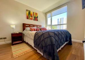 um quarto com uma cama e uma grande janela em Hermoso departamento a pasos de UdeC em Concepción