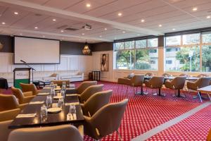 een conferentiezaal met tafels en stoelen en een projectiescherm bij Hotel Armitage and Conference Centre in Tauranga