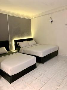 duas camas num quarto de hotel com lençóis brancos em Andiana Hotel & Lodge - Kota Bharu City Centre em Kota Bharu