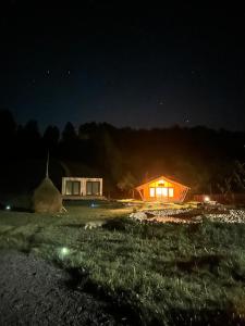 a lit up cabin at night with a mountain in the background at Rai Village in Băniţa
