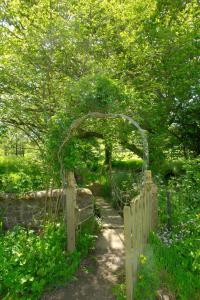 un jardín con un arco y una puerta de madera en Mill House Barn, en Okehampton