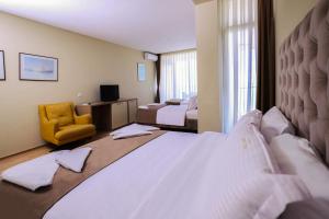 a hotel room with a bed and a yellow chair at Gjilani Premium Hotel in Shëngjin