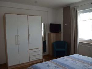 a bedroom with a white cabinet and a blue chair at Cutter in the shiphouse in Hooksiel
