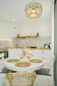 Il comprend une cuisine avec une table blanche, des chaises et un lustre. dans l'établissement Apart Harmony- Apartament Kaprów 6, à Puck